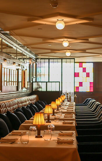 A bustling restaurant with a spacious long table and comfy chairs, inviting you to enjoy a delightful meal with friends and family
